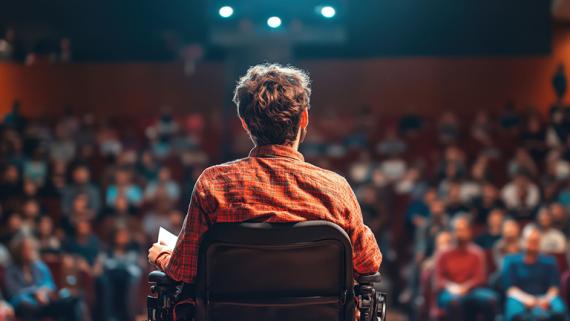 A young man in a wheelchair speaking to a crowd