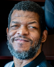 Ski Adams, a dark-skinned man in a wheelchair with a graying beard