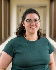 Hilary Casey a white women with brown, curly hair, wearing glasses and a green shirt. 