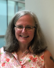 Val Mazzotti, KUCD Affiliated Investigator and SPED Distinguished Professor: A woman with long gray hair, square-rimmed glasses, and a pink floral-print shirt
